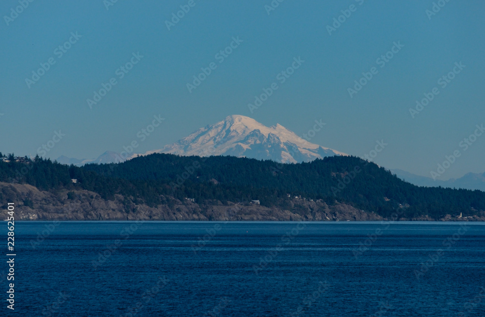 view of mount baker over the island on the ocean on a sunny day