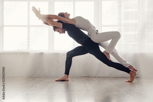 Fit young couple doing acro-yoga in modern studio photo