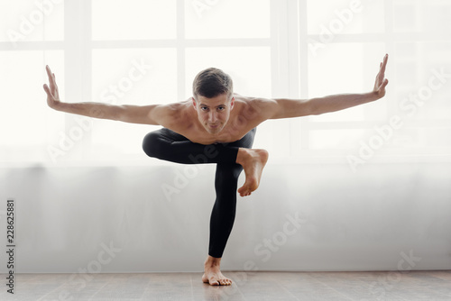 Flexible athletic man doing yoga asana at home