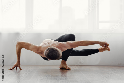 Strong flexible man doing morning yoga exercises photo