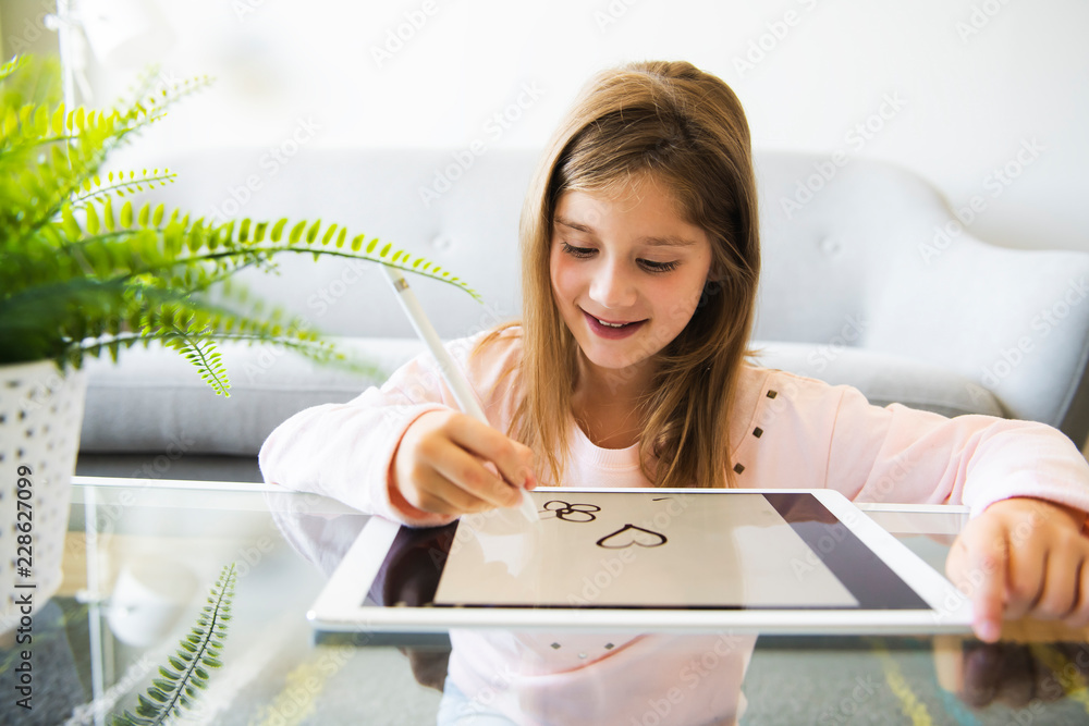© Louis-Paul Photo - kid in living room at home and using digital tablet to draw