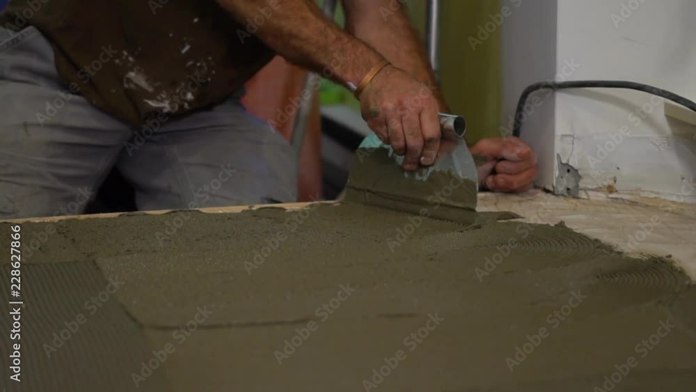 Closeup of worker spreading mortar for new ceramic floor Closeup of worker spreading mortar for new ceramic floor