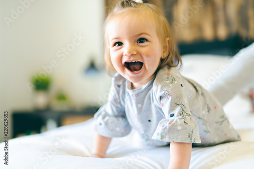 Cute little baby girl on bed at home