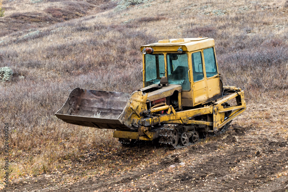 Yellow crawler bulldozer standing on a hill