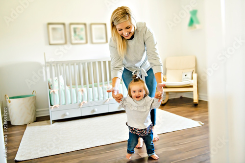 little baby girl first steps with the help of mother photo