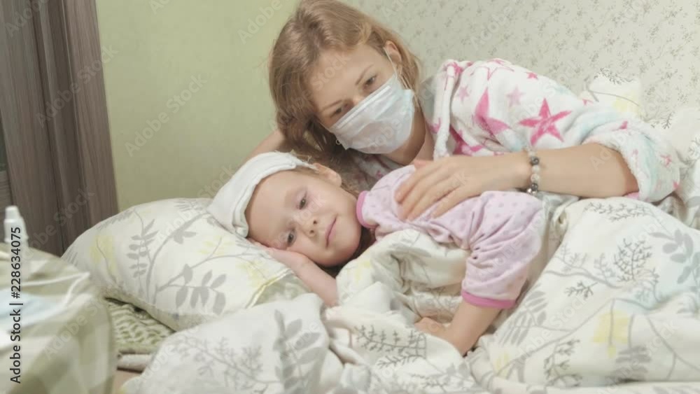 Sick girl with fever Child with fever lying in bed with mother Sick girl with fever Child with fever lying in bed with mother