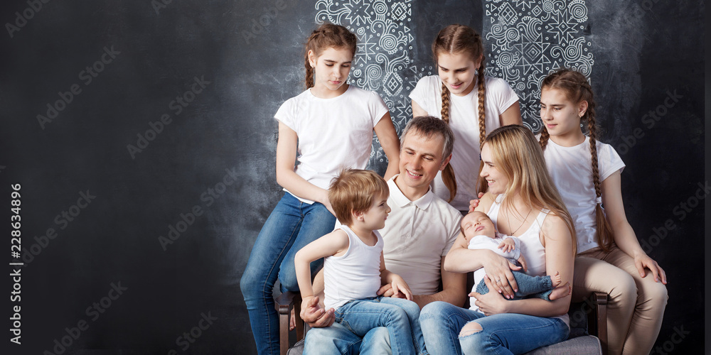 Big family portrait.  Parents with five children. Mother and father with newborn baby, toddler and teenagers. Concept of big happy family. Image with copyspace