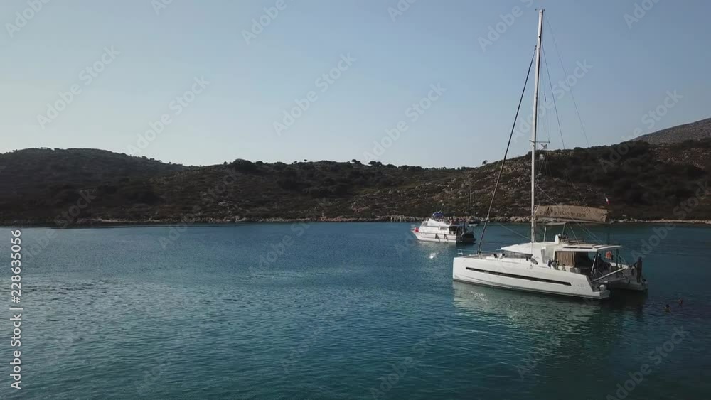 Aerial view orbital, Sailboats anchored in a calm lonely bay with sun reflections at sunset hours Aerial view orbital, Sailboats anchored in a calm lonely bay with sun reflections at sunset hours