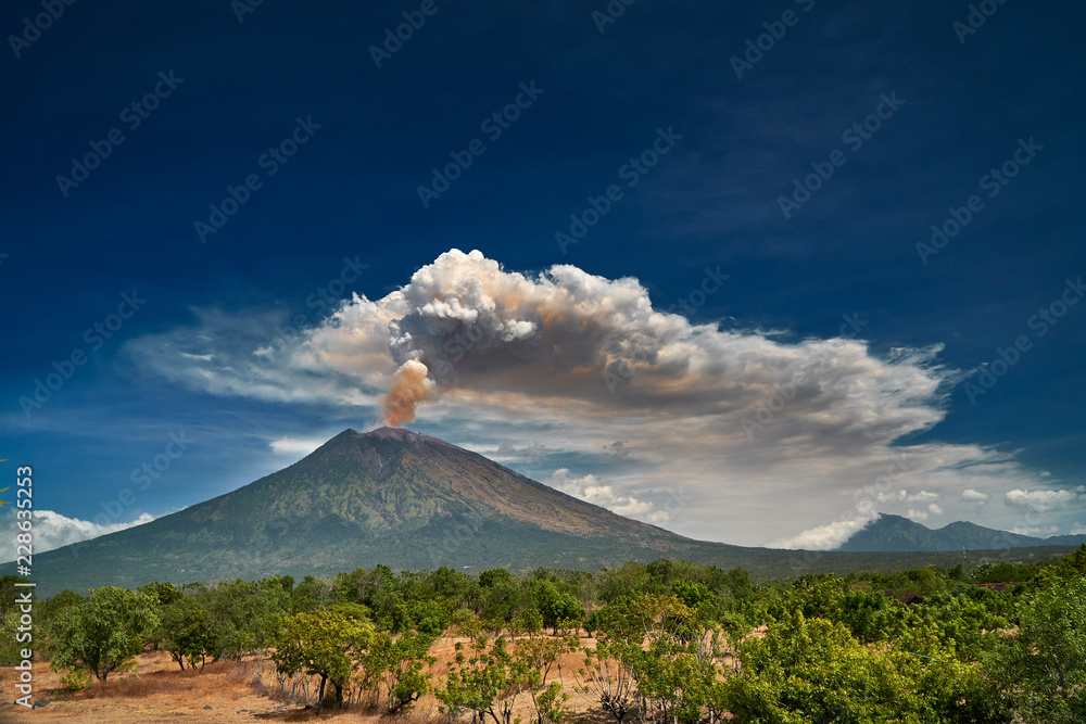 29 June 2018, Bali, Indonesia.Mount Agung volcano dramatic eruption over dark blue sky . Massive clouds of ash higlighted by magma. - obrazy, fototapety, plakaty 