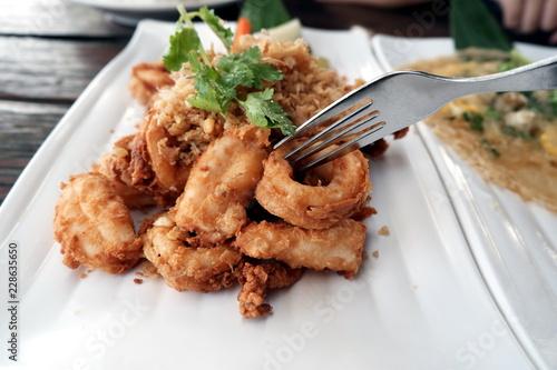 Crispy squid deep fry with fork on white plate ,close up 