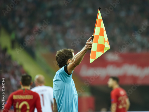 Assistant of football referee with raised flag.