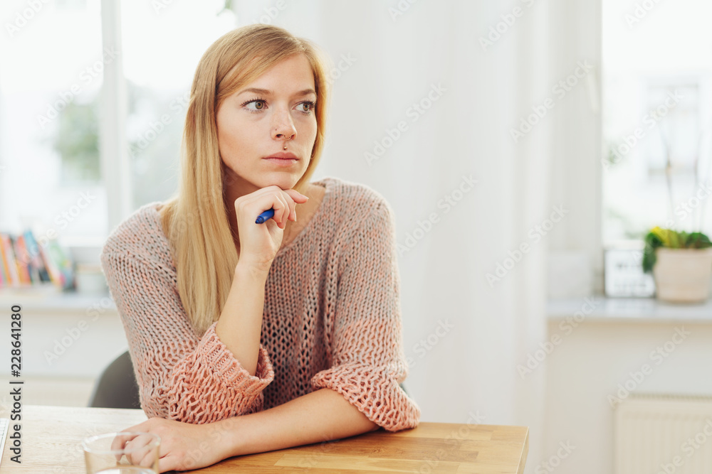 Thoughtful blond woman sat at table