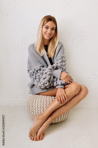 Full-lenght portrait of lovely happy woman with blond hair and long beautiful legs wearing lavand pullover sitting over isoted background photo