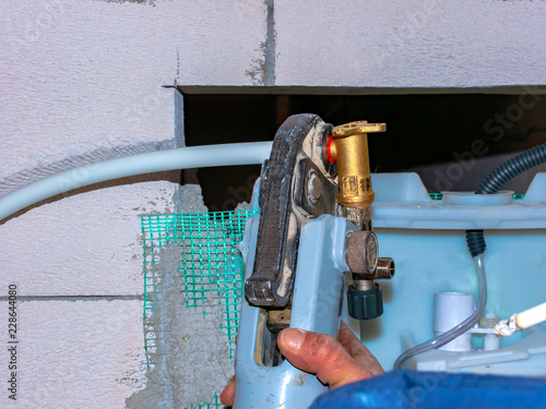 Worker with multilayer pipe presser is assembling the metal bushings of the fittings