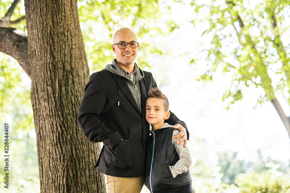 A father and son outside close to a tree A father and son outside close to a tree