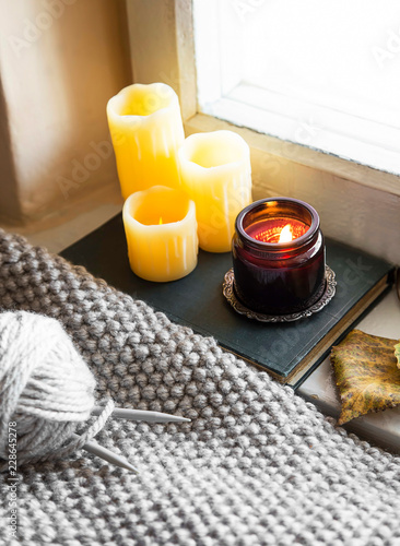 Cozy fall indoor decoration setting with candles and knitting blanket