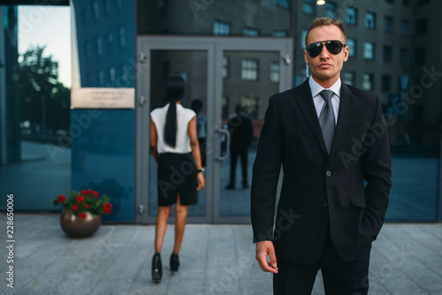 Serious bodyguard in suit and sunglasses, guarding