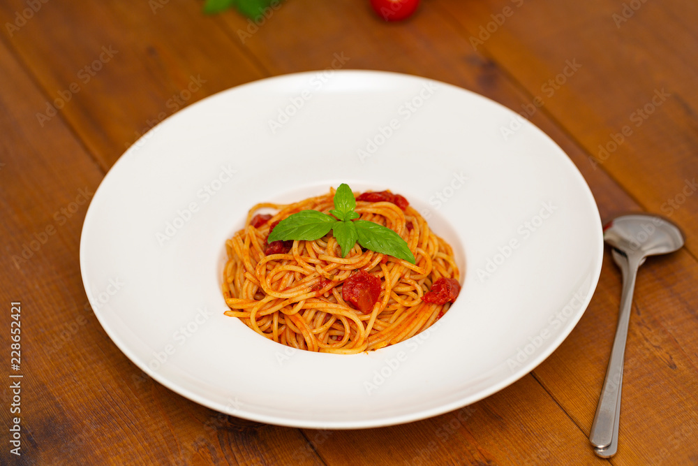 Plate of delicious Italian spaghetti pasta with fresh basil leaves, with meat, tomato sauce, vegetables and grated parmesan cheese Plate of delicious Italian spaghetti pasta with fresh basil leaves, with meat, tomato sauce, vegetables and grated parmesan cheese