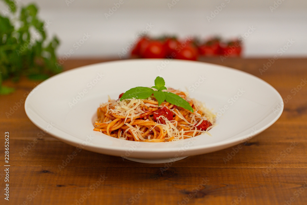 Plate of delicious Italian spaghetti pasta with fresh basil leaves, with meat, tomato sauce, vegetables and grated parmesan cheese Plate of delicious Italian spaghetti pasta with fresh basil leaves, with meat, tomato sauce, vegetables and grated parmesan cheese