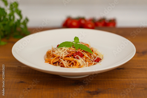 Plate of delicious Italian spaghetti pasta with fresh basil leaves, with meat, tomato sauce, vegetables and grated parmesan cheese