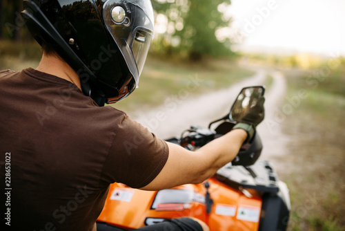Atv rider adjusts the rearview mirror before trip