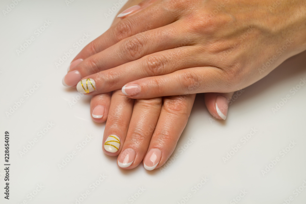 French manicure and nail gel Polish. The decoration of the nail white and gold decor. Top view Close-up photography