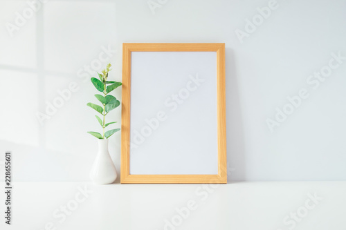 Mock up portrait photo frame with green plant on table, home decoration.