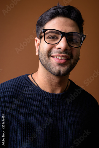 Young handsome Indian man against brown background © Ranta Images