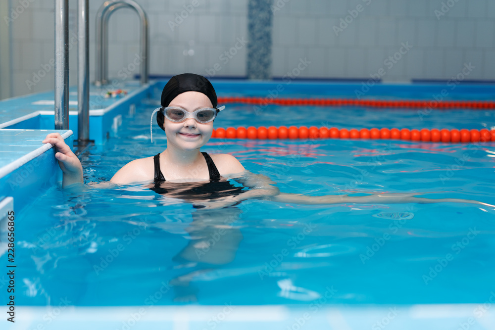 swimming lessons for children in the pool - beautiful fair-skinned girl swims in the water