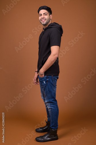 Young handsome Indian man against brown background © Ranta Images