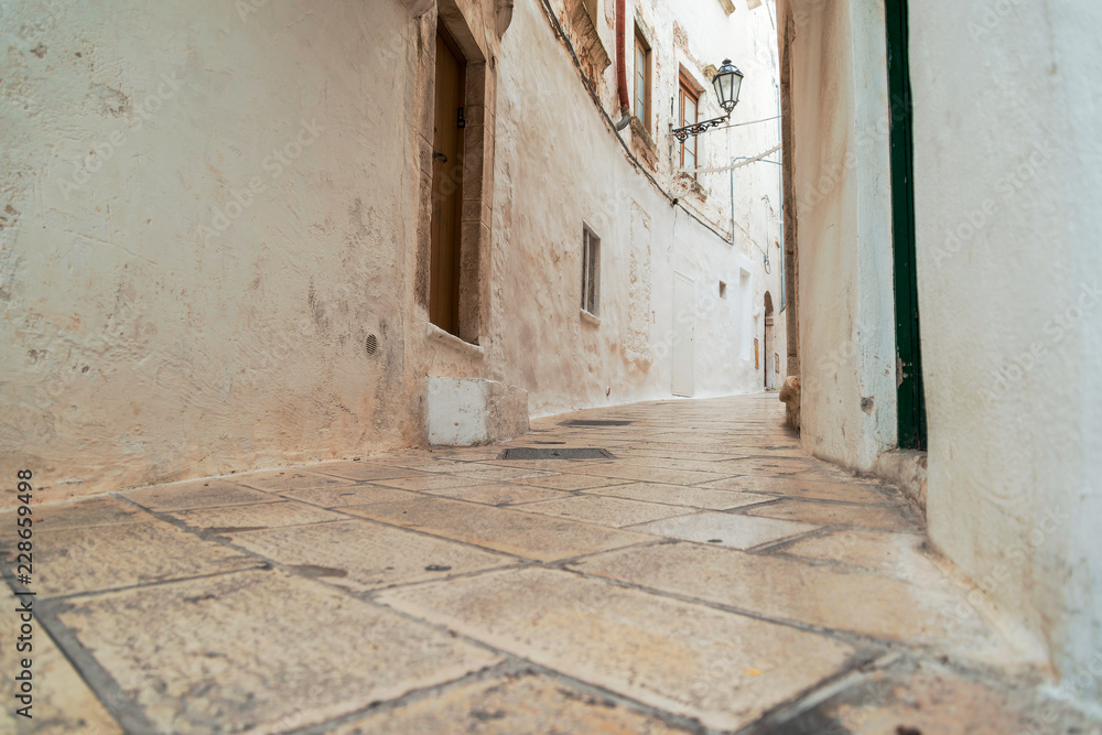 Little alley in the medieval white village of Ostuni at sunset