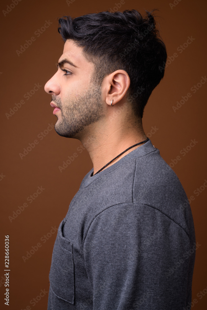 Fototapeta premium Young handsome Indian man against brown background