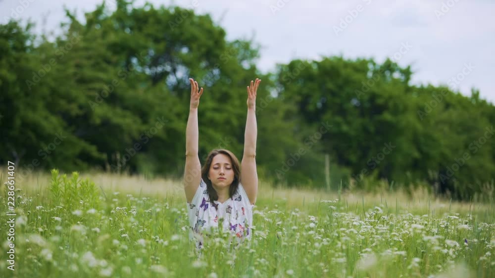 Young woman in green grass making buddhist practice, namaste after meditation Young woman in green grass making buddhist practice, namaste after meditation