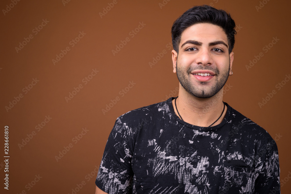 Young handsome Indian man against brown background Young handsome Indian man against brown background