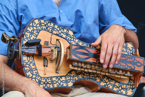 The wheel lyre in the hands of the playing musician.