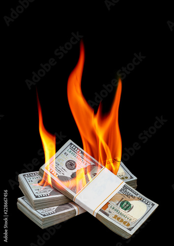 New US Dollar bundles burning with flame including copyspace on black background 