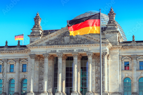 The German flag streaming in front of the German parliament building, the Reichstag at Berlin, Germany.