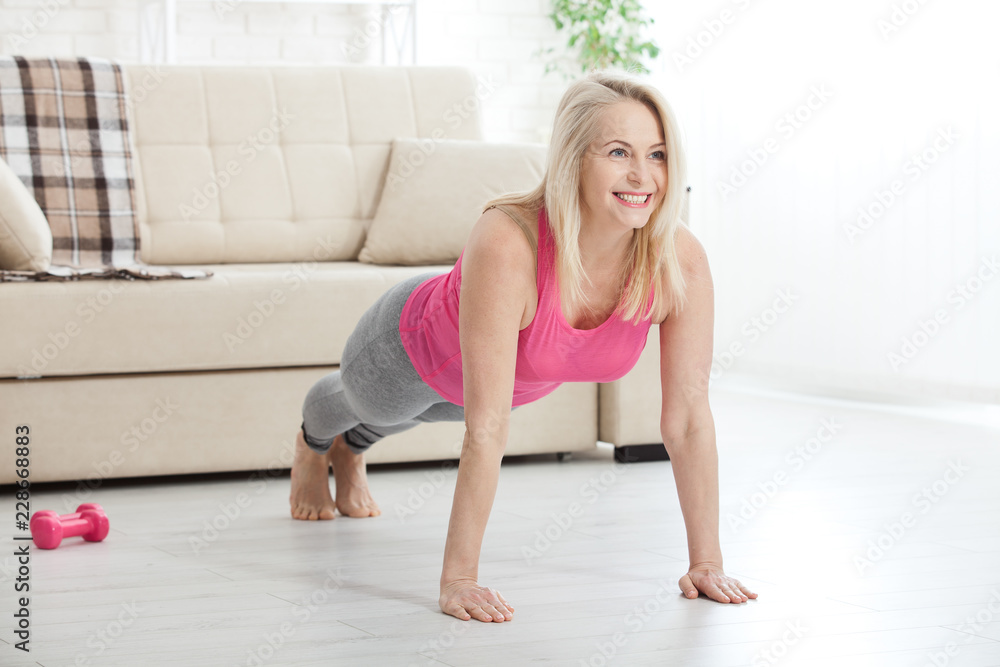 Happy woman in her 50s stretching for exercise at home. Joy of life and freedom in movement, concept. Selective focus.
