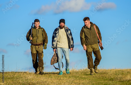 Brutal hobby. Group men hunters or gamekeepers nature background blue sky. Guys gathered for hunting. Men carry hunting rifles. Hunting as hobby and leisure. Hunters with guns walk sunny fall day