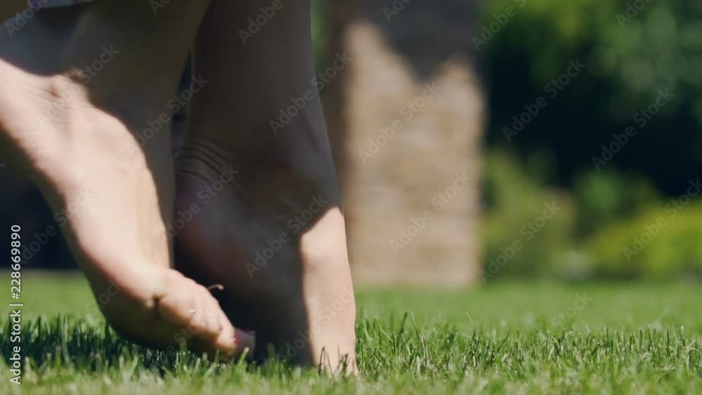 Female feet carefully walk on toes upon green grass, slow motion spring park Female feet carefully walk on toes upon green grass, slow motion spring park