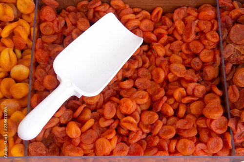 Dried apricots on the counter of the store. Plastic white scoop for typing is on top. fruit background photo