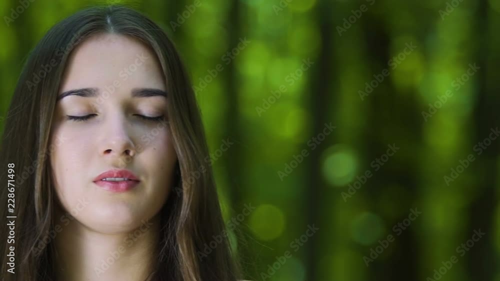 Woman meditating with closed eyes in forest, camera pan, place for ad text slow Woman meditating with closed eyes in forest, camera pan, place for ad text slow