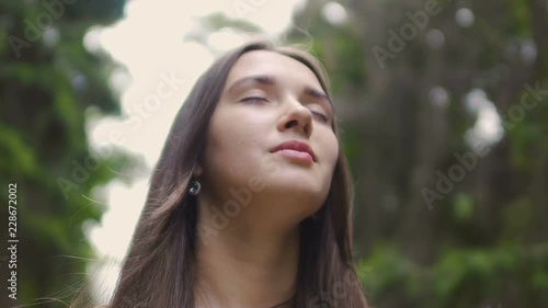 Woman in closed eyes low angle shot, beautiful brunette feels nature oneness