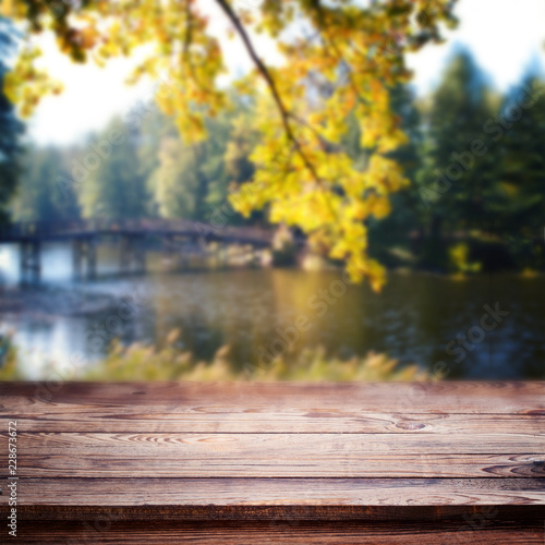 Empty table over blurred trees and river as background, product display template. Selective focus