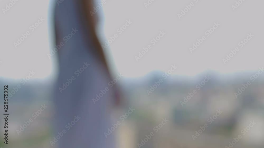 Woman in white dress watches city from above, rack focus background urban view Woman in white dress watches city from above, rack focus background urban view