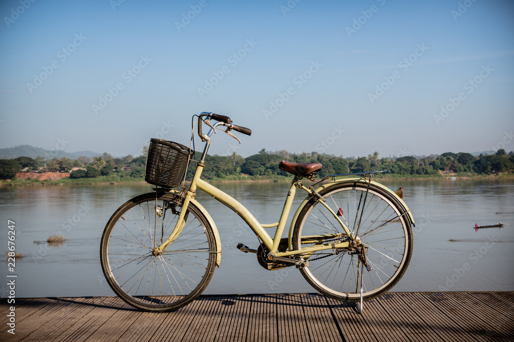Fototapeta premium Bicycle near lake during sunset.Vintage bike near the lake in the evening, warm sunset view.