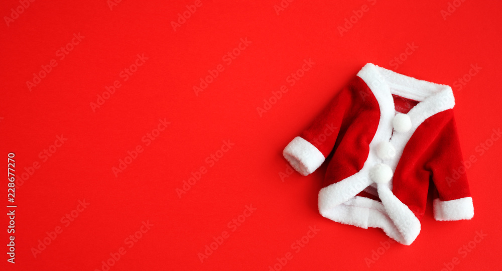 Christmas background Santa Claus (Saint Nicholas) mini coat suit costume with white cuffs flat lay isolated on vivid red background. Concept photo for Merry Christmas Winter holidays celebration. Christmas background Santa Claus (Saint Nicholas) mini coat suit costume with white cuffs flat lay isolated on vivid red background. Concept photo for Merry Christmas Winter holidays celebration.