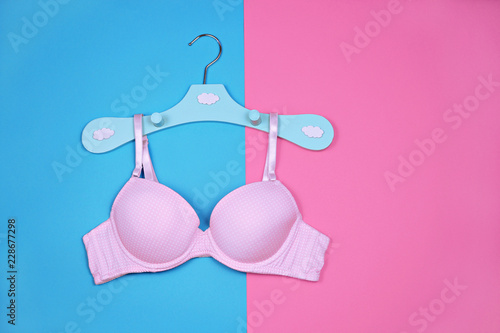 Bra on hanger on blue pink background