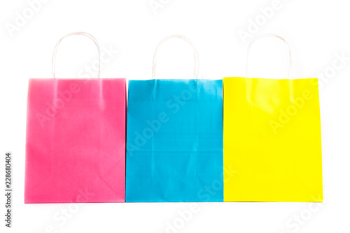 Many blank paper shopping bags of different colors, pink, blue and yellow isolated on white background. Blank colorful packets. Black friday sale concept. Close up copy space.