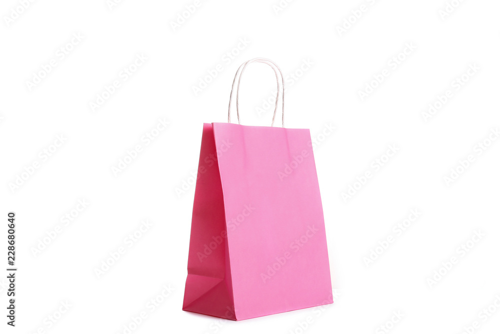 Single blank shoppong bag standing on isolated white background. Pink paper packet reflecting studio light. Black friday sale concept. Close up, copy space for text.